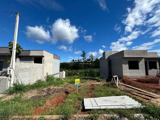 Vista externa de duas construções em um terreno com vegetação.