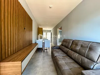 Hall de entrada com sofá e painel de madeira na residência.