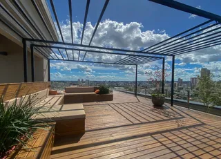 Vista panorâmica da varanda com deck de madeira e vista da cidade.
