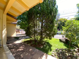 Vista externa de um jardim com árvores e um caminho pavimentado.