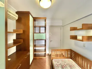 Quarto com armário e cabeceira de madeira em ambiente interno.