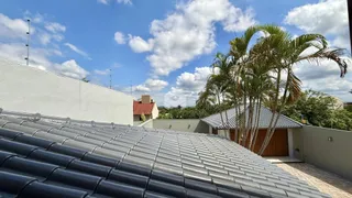 Vista da fachada de um imóvel com telhado de metal e palmeiras no céu azul.