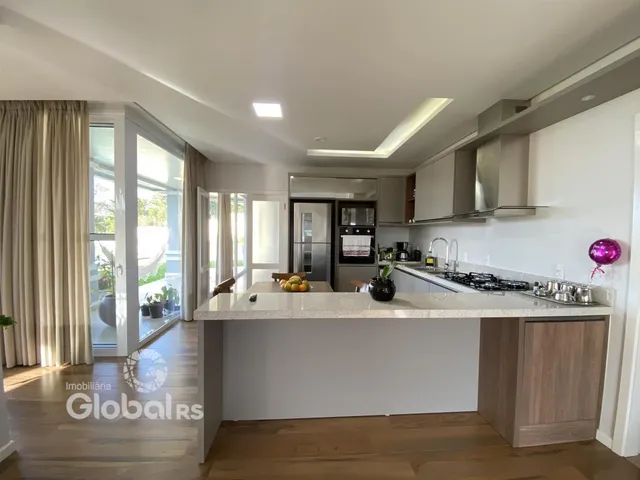 Sala de estar e cozinha moderna com piso de madeira clara e grandes janelas.