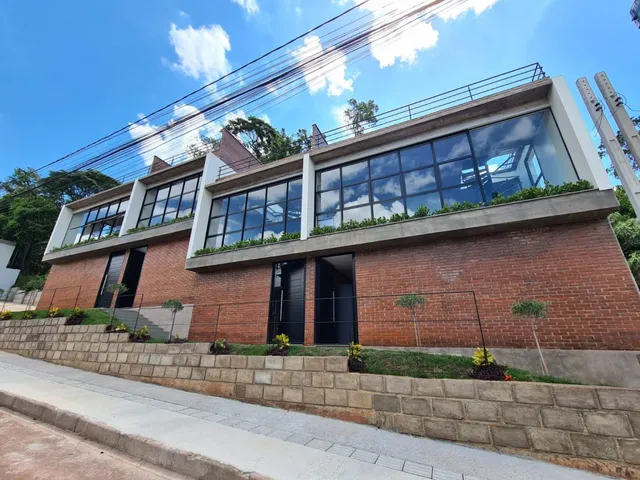 Fachada de um imóvel residencial em tijolos vermelhos com grandes janelas.