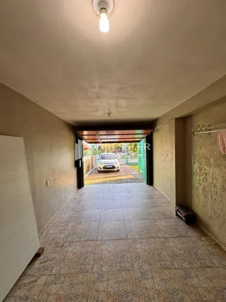 Corredor interno com piso de cerâmica que leva a uma área externa.