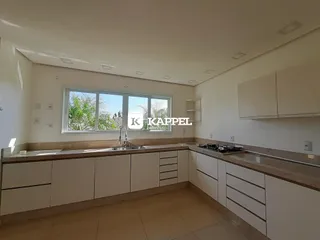 Cozinha com armários brancos e bancadas claras em um imóvel.