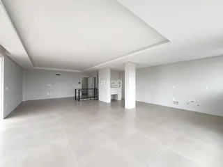 Ambiente interno de uma sala ampla com piso claro e paredes brancas.