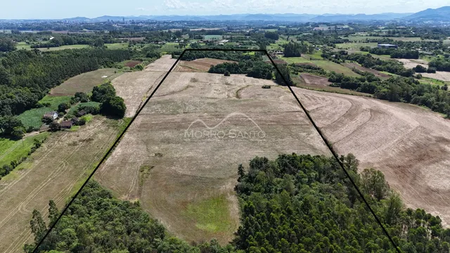 Vista aérea de uma propriedade rural com áreas de vegetação e campos abertos.