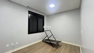Ambiente interno de uma sala com paredes cinzas e piso de madeira clara.
