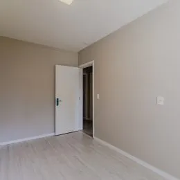 Interior de um cômodo com piso claro e parede neutra.