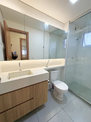 Interior de um banheiro moderno com bancada e box de vidro.