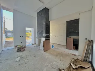 Interior de uma sala em construção com piso de concreto e paredes brancas.