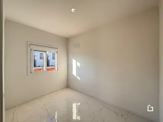 Ambiente interno de uma sala com piso de porcelanato branco e paredes brancas.