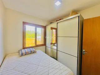 Quarto com cama e guarda-roupa de armário branco.