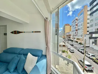 Sala de estar com sofá azul e vista para a rua.