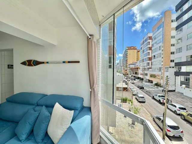 Sala de estar com sofá azul e vista para a rua.