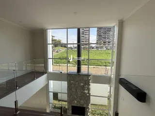 Vista de um imóvel com grande janela de vidro para um gramado externo.