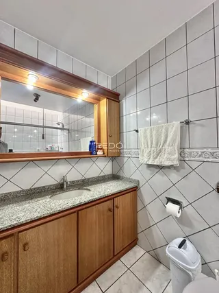 Banheiro com revestimento de azulejos e bancada de granito.