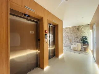 Hall de entrada com portas de elevador em madeira na residência.