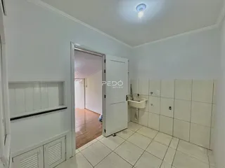 Vista de um corredor com porta aberta mostrando um ambiente interno com piso de madeira.