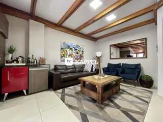 Sala de estar com sofá e mesa de centro em ambiente com vigas de madeira expostas no teto.