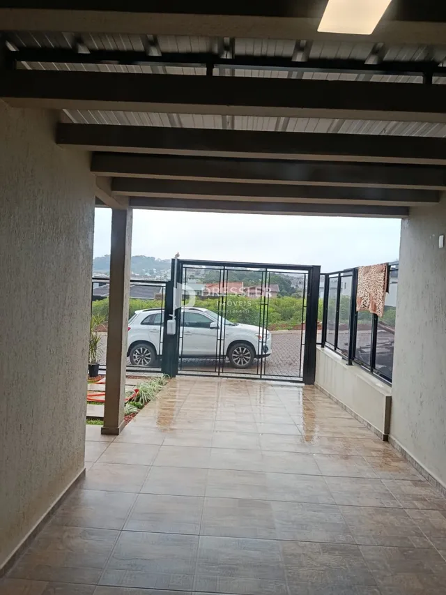 Área externa com piso de cerâmica e portão de entrada.