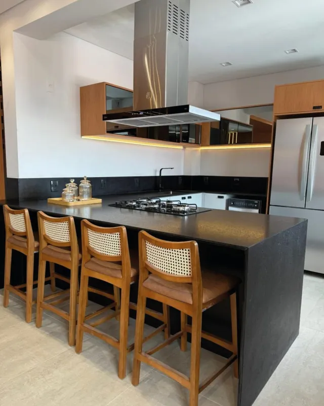 Cozinha moderna com ilha central e armários de madeira escura.