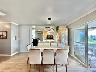 Sala de jantar com mesa de madeira e cadeiras brancas em um imóvel em Lajeado.