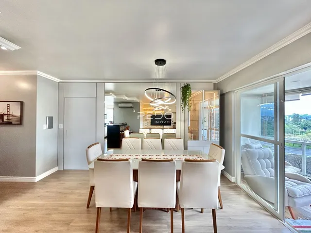 Sala de jantar com mesa de madeira e cadeiras brancas em um imóvel em Lajeado.