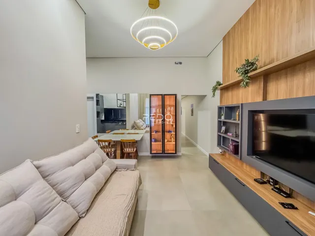 Sala de estar moderna com sofá branco e decoração de madeira clara.
