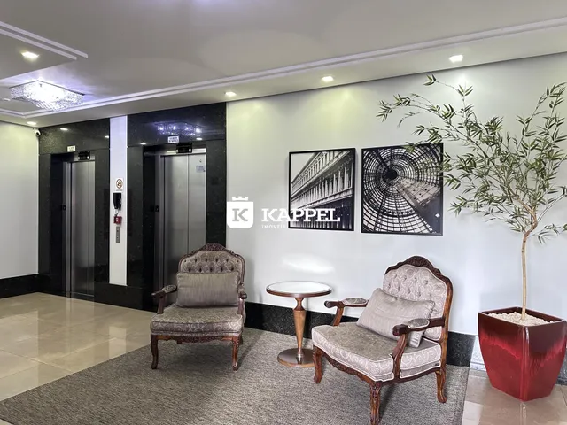 Uma sala de estar com duas poltronas ornamentadas e uma mesa redonda.