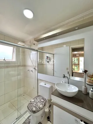 Foto de um banheiro com box de vidro e louças brancas.