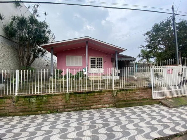 Fachada de uma casa em Lajeado, Brasil, com cerca branca e muro de tijolos.