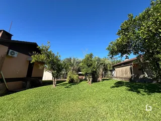 Vista externa de um jardim gramado com árvores sob um céu azul claro.