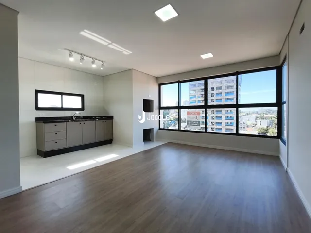 Sala de estar ampla com piso de madeira e grande janela de vista para a cidade.