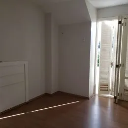 Interior de um cômodo com piso de madeira e paredes brancas.