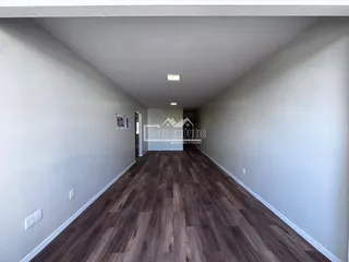 Corredor interno de uma residência com piso de madeira escura.
