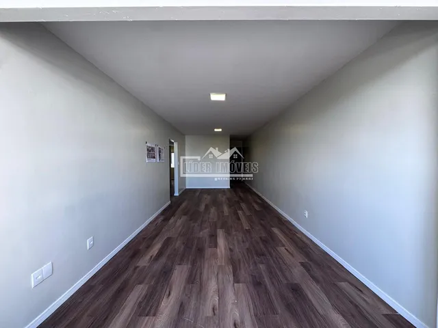 Corredor interno de uma residência com piso de madeira escura.