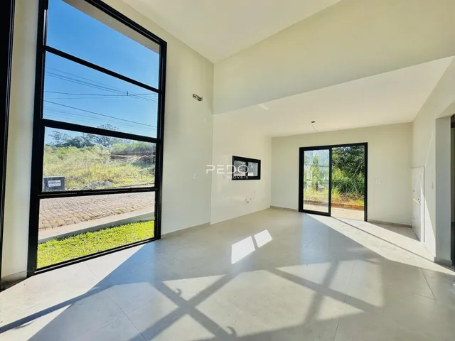 Interior de uma sala de estar com grande janela de vidro voltada para o exterior.