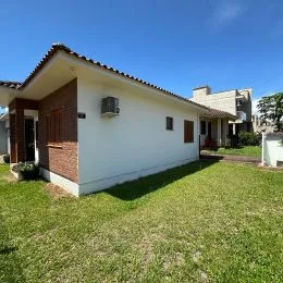 Fachada de uma casa branca com telhado de telhas em um dia ensolarado.