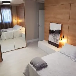 Quarto com cama de casal e espelho em ambiente interno.