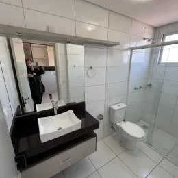 Foto de um banheiro com revestimento branco e bancada escura.