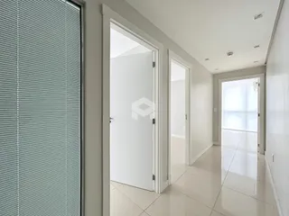 Vista de um corredor interno com portas brancas em uma residência.