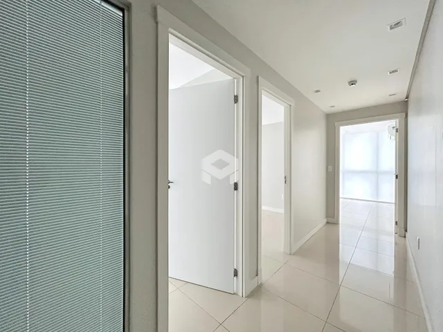 Vista de um corredor interno com portas brancas em uma residência.