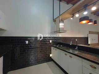 Cozinha com revestimento de tijolos escuros e armários brancos.