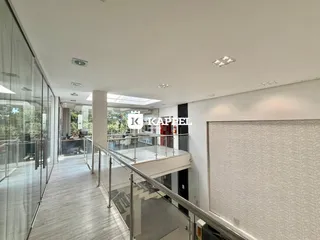 Corredor interno com piso claro e guarda-corpo de vidro.