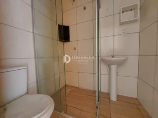 Foto interna de um banheiro com piso de cerâmica e box de vidro.