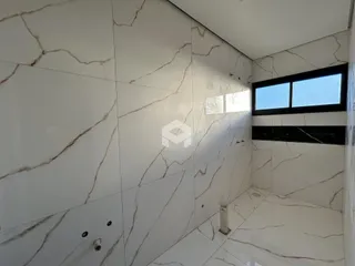 Parede revestida com azulejos brancos com veios marrons em um ambiente interno.
