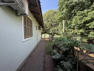 Vista externa da casa em Lajeado com jardim e caminho de cascalho.