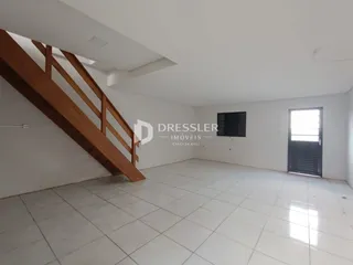 Interior de uma sala com escadaria de madeira e piso de cerâmica.